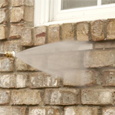 An employee with Xtreme Home Improvement uses a pressure washer to clean the outside of a house
