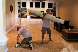 Xtreme Home Improvement technicians remove carpet from a flooded basement